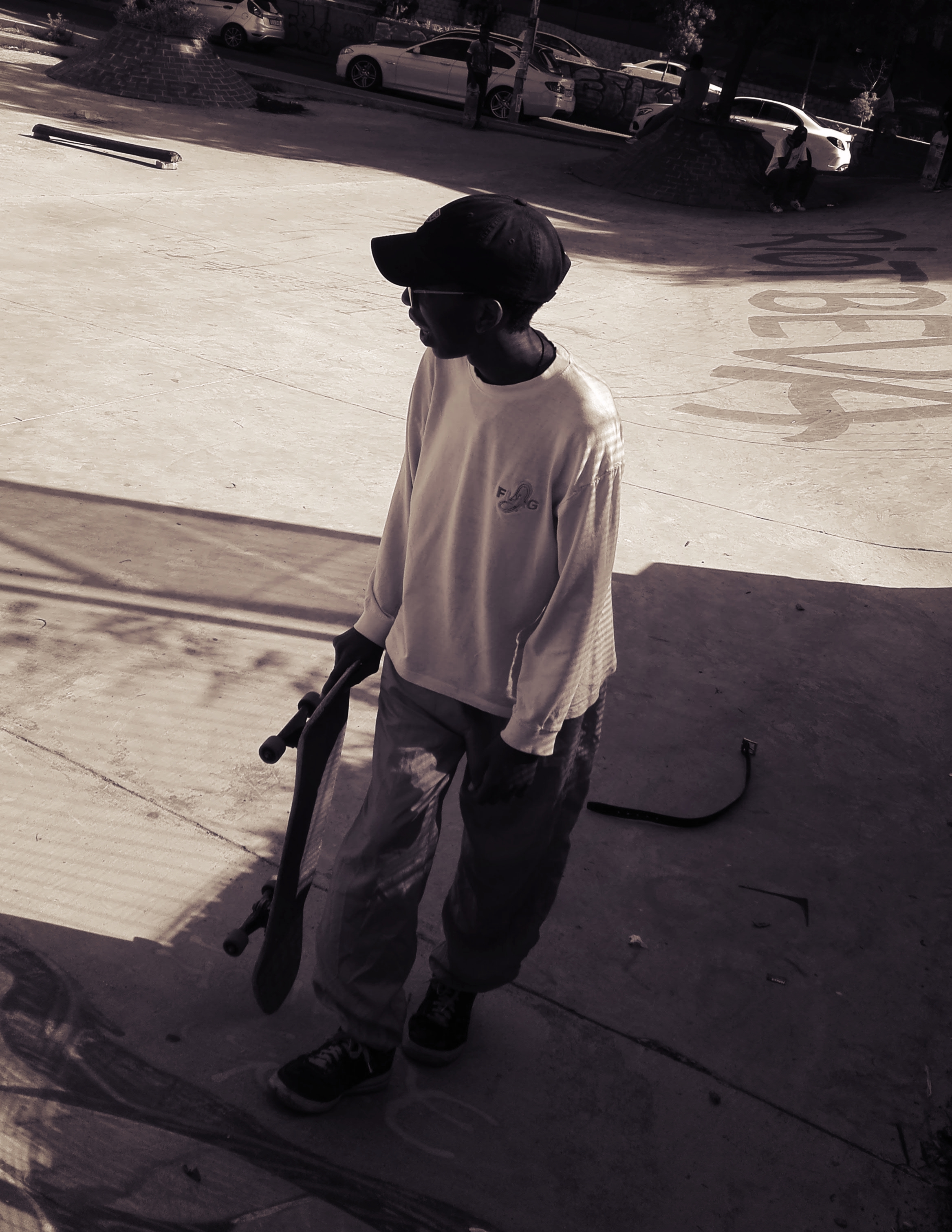 sifiso holding a skateboard wearing a cap with glasses on
